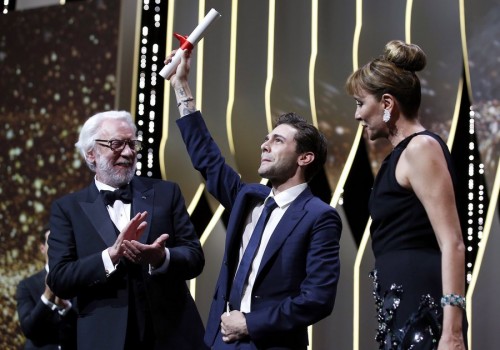 epaselect epa05323897 Canadian director Xavier Dolan (C) reacts after receiving the Grand Prix award for 'Juste la Fin du Monde' (It's Only the End of the World) from Italian actress Valeria Golino (R) and Canadian actor Donald Sutherland (L) during the Closing Award Ceremony of the 69th Cannes Film Festival, in Cannes, France, 22 May 2016. For the first time in the festival history, the Golden Palm winning movie will be screened at the closing ceremony. EPA/SEBASTIEN NOGIER